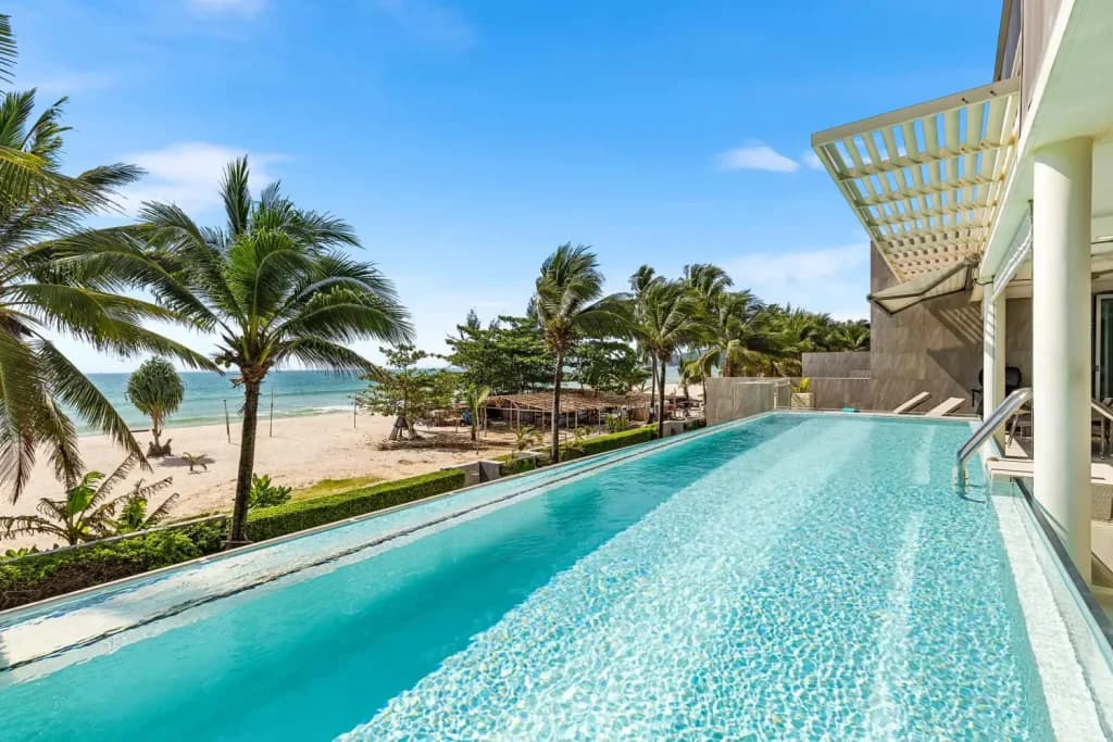 Infinity pool overlooking a tropical beach with palm trees in Phuket, Thailand